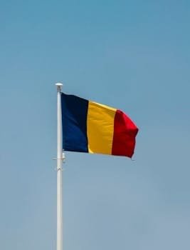 Vibrant Romanian flag flying on a flagpole in Bucharest against a clear sky.