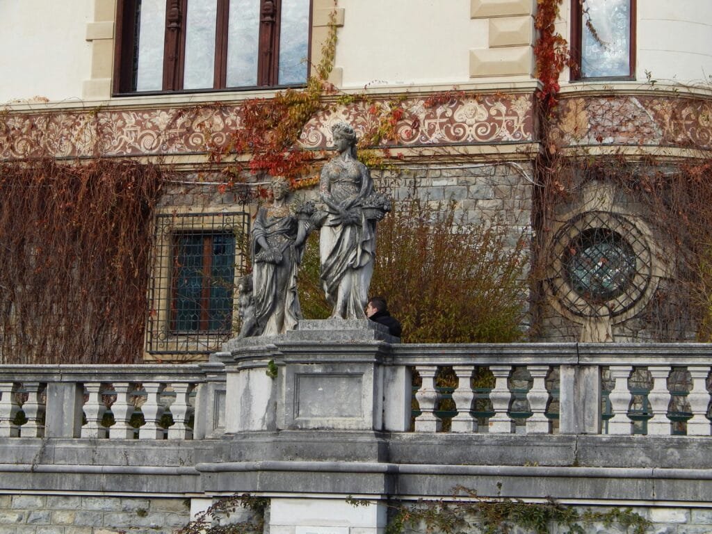 Elegant classical sculptures adorn a historic Romanian building facade covered in ivy.